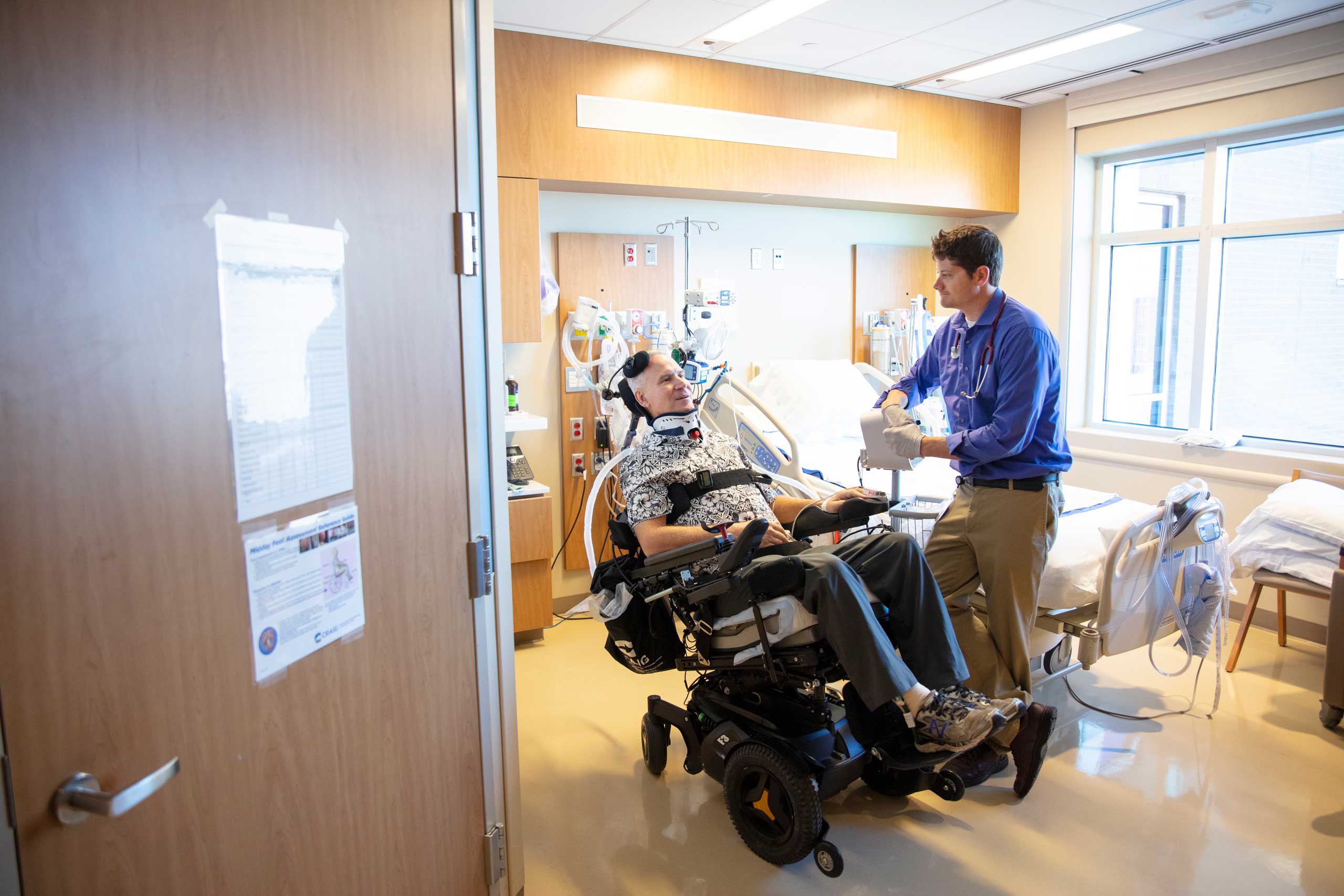 patient in a wheel chair being assisted by a staff