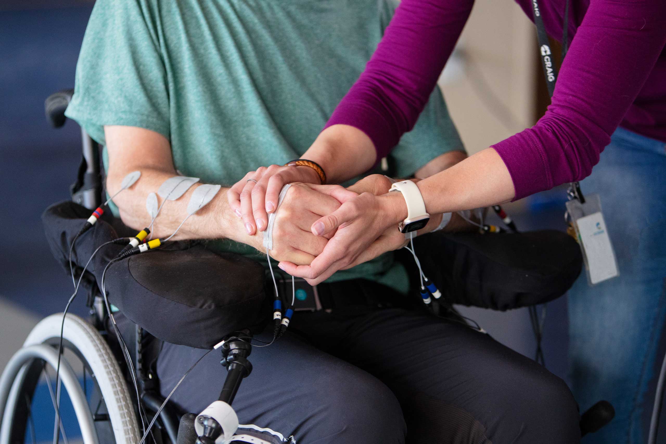 staff holding a wheelchair patient's hand close up