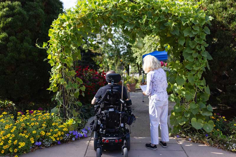 patient in a wheelchair an their guest enjoying a nice day in a garden