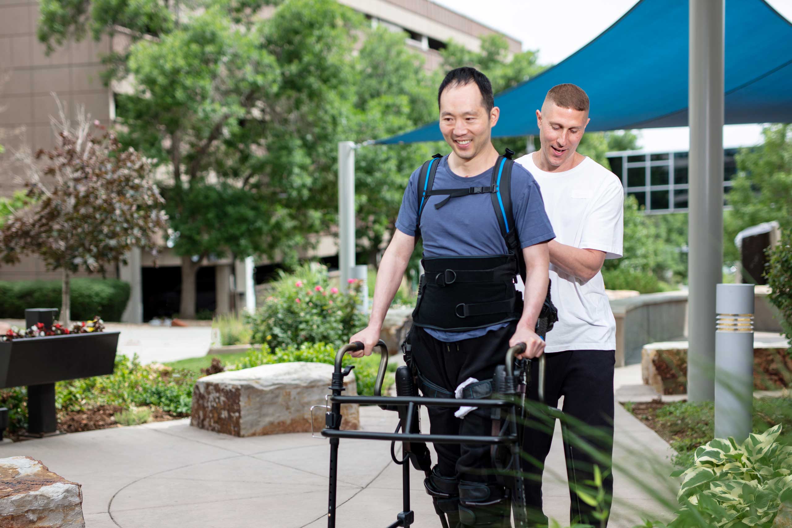 patient walking outside with a walker being assisted by a staff member