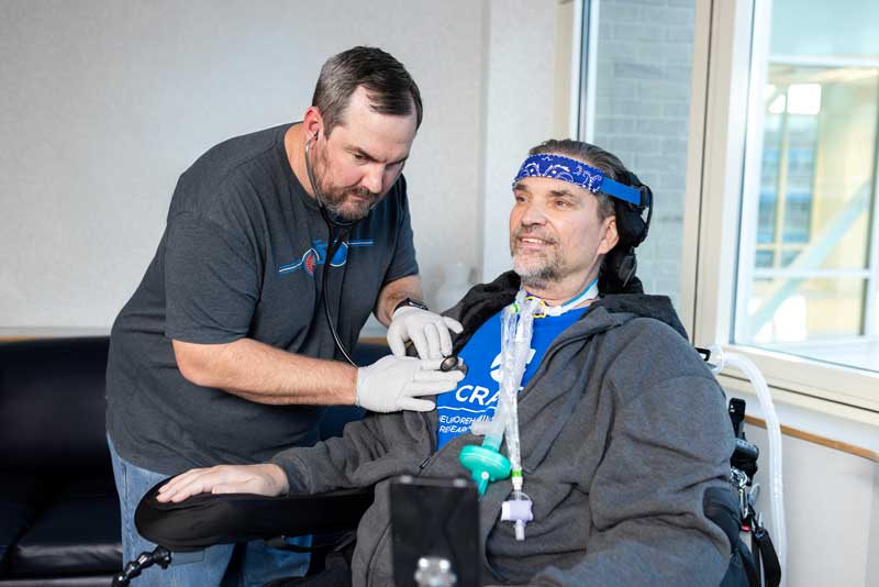 staff member checking the heart beat of a patient in a wheel chair